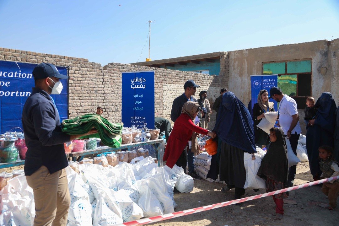 Families collect food supplies beneath Education, Hope, Opportunity banners